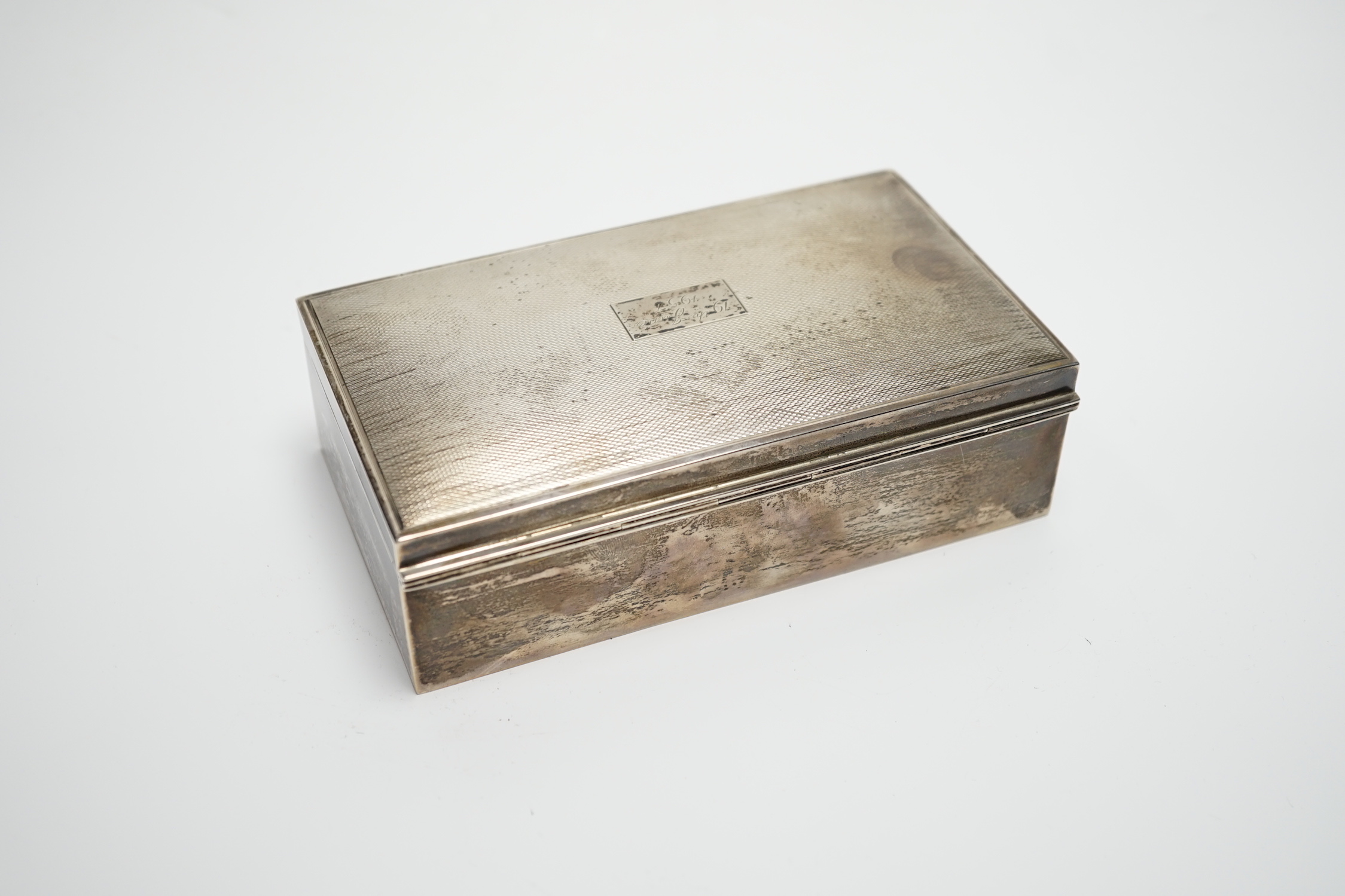 A modern part engine turned silver cigarette box, with engraved inscription, 16cm and a silver serviette ring.